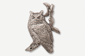 A silver owl sitting on the branch of a tree.