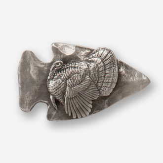 A silver turkey is sitting on top of an arrowhead.