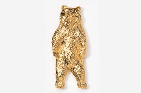 A gold bear is standing up against the wall.