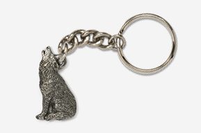 A silver key chain with a wolf sitting on top of it.