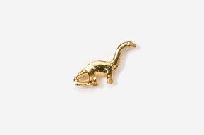 A gold plated dinosaur charm is sitting on top of the ground.