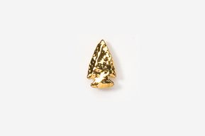 A gold colored metal arrowhead on top of a white surface.