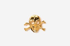 A gold skull and crossbones pin on a white surface.